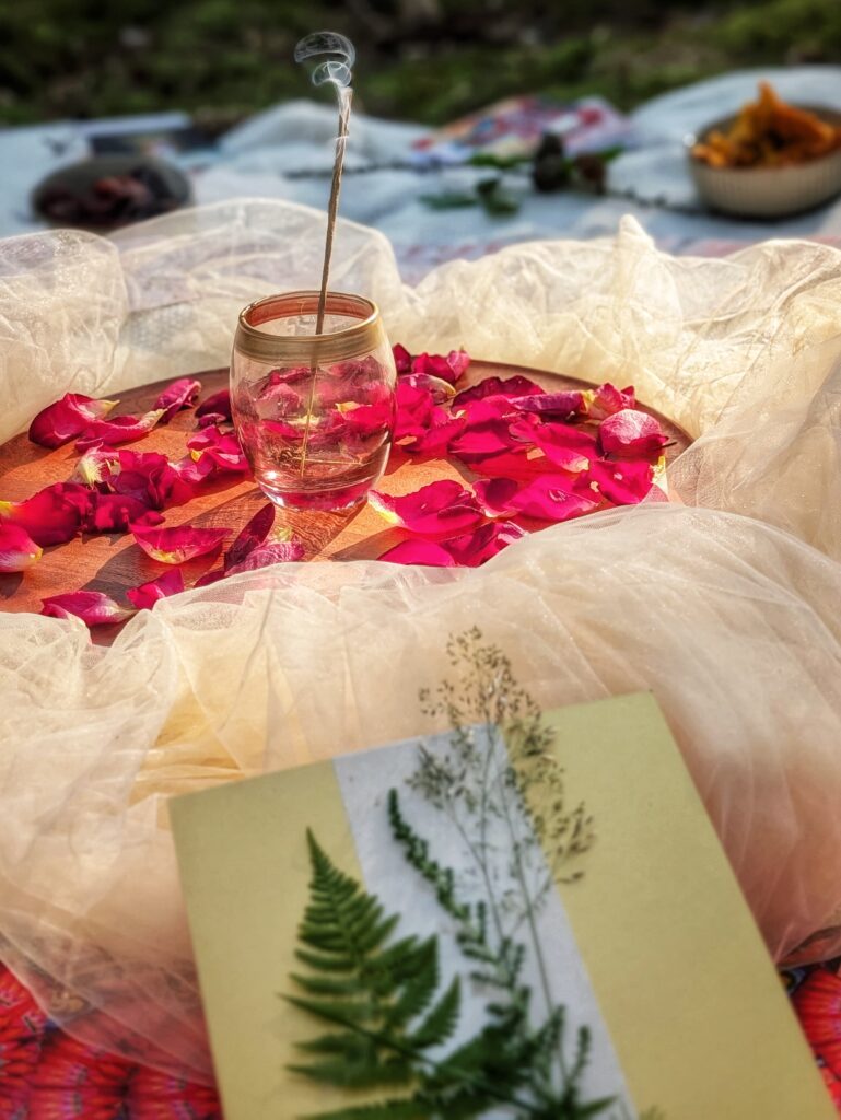 Waldzeremonie-Frequenz-von-Mutter-Erde Zeremoniekreis mit Rosenblüten, Räucherstäbchen und einer Farnkarte im Wald