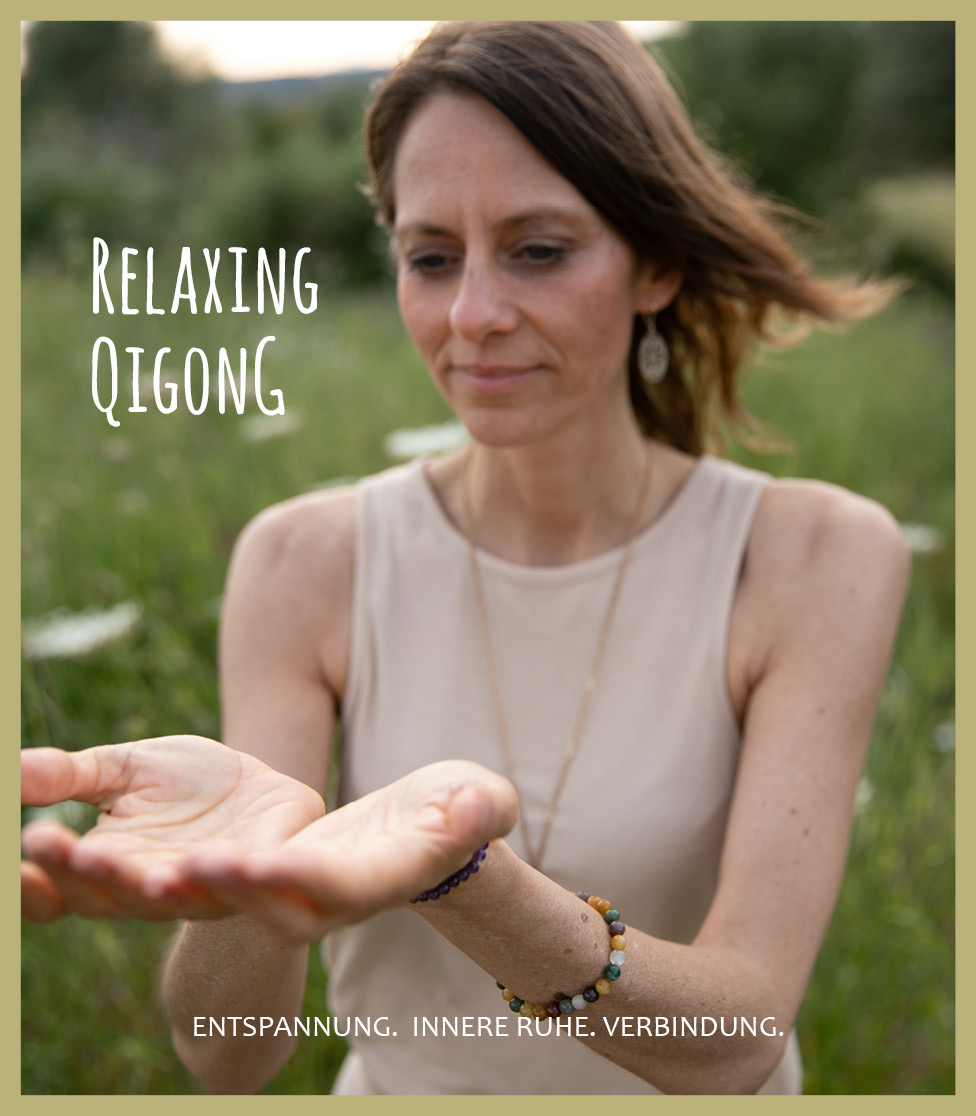 Frau übt eine Qigong-Bewegung, ihre Hände sind so gehalten, dass sie das Qi trägt. Sie steht in einer Wiese